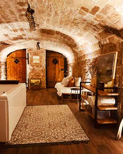 Cave voûtée restaurée en spa avec baignoire balnéo, lumière tamisée et ambiance zen.