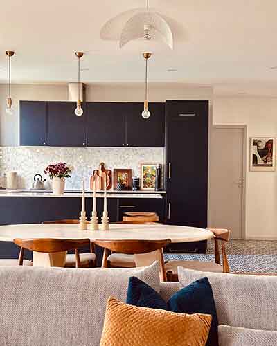 Salon rénové avec canapé coloré, coin repas et cuisine ouverte aux façades bleu profond.