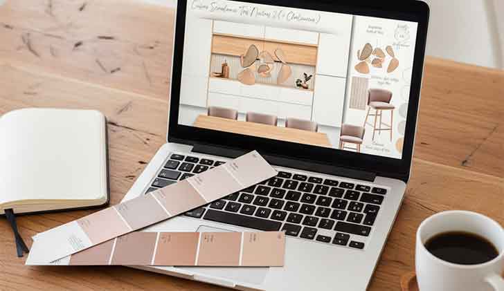 Bureau en bois clair avec un MacBook affichant un moodboard réalisé par Alice Roux, décoratrice d’intérieur, accompagné d’un calepin et d’une tasse de café.
